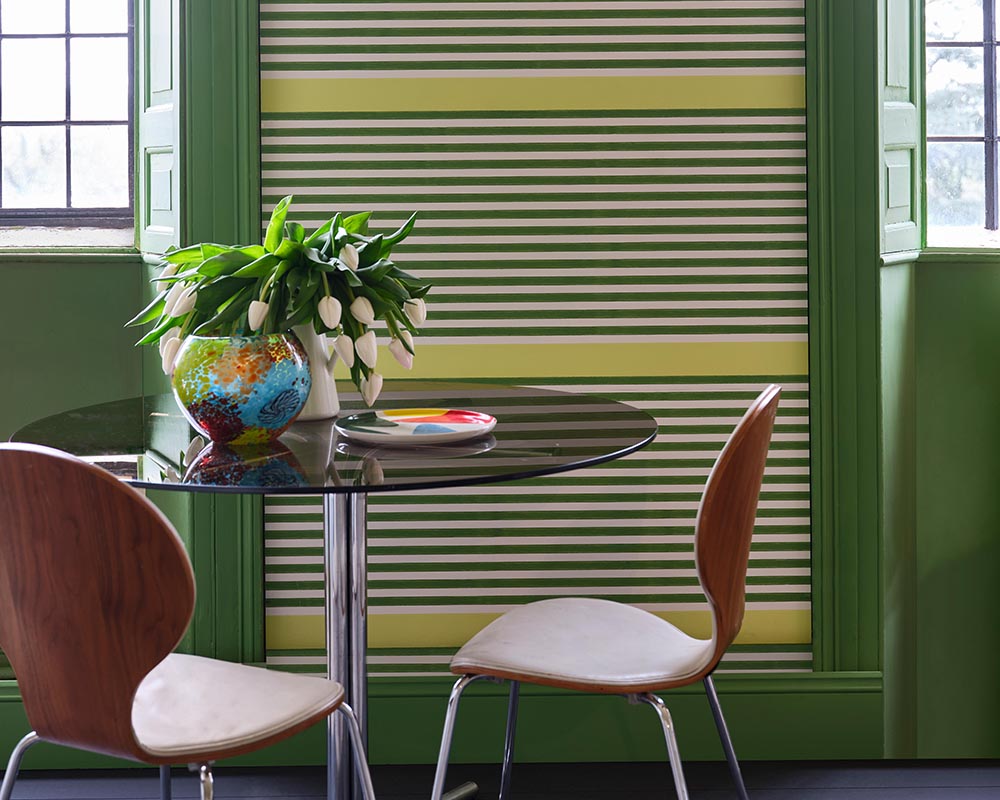 Raw Tomatillo CB6 paint by Farrow & Ball on woodwork in a dining room with a bold wallpaper
