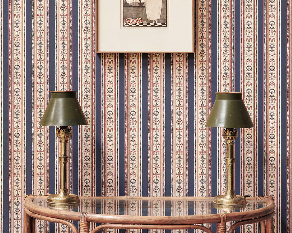 Barneby Gates Folk Stripe Wallpaper in a room with a side table, lamps and a frame on the wall