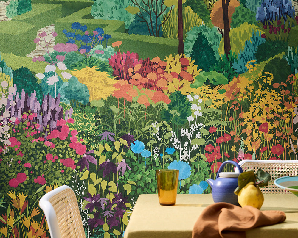 Colourful scene with a table and chairs, featuring the vibrant Little Greene Castle Garden Mural Wallpaper with floral and nature-themed design.