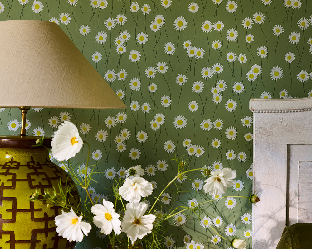 Little Greene Moon Daisies floral wallpaper with daisies, a lamp, and a vase with cosmos flowers on the green background wallpaper