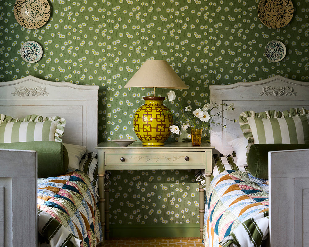 Two twin beds with decorative headboards against the green Little Greene Moon Daisies floral Wallpaper