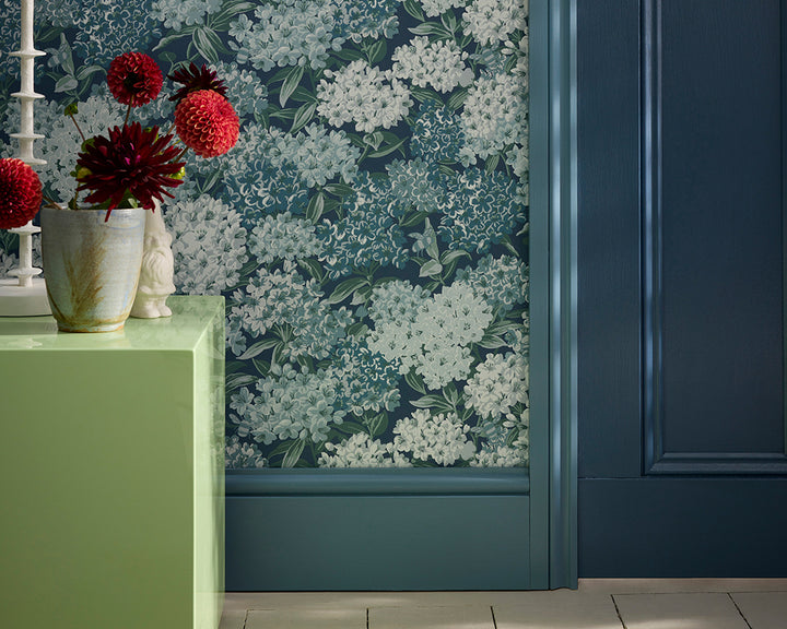 Little Greene Rhododendron Walk Floral wallpaper with a green cabinet and decorative items.