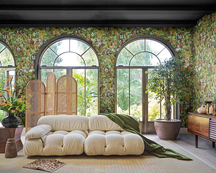 Modern living room with a beige sofa, decorative pillows, and the jungle-patterned Cole & Son Injisuthi Wallpaper.