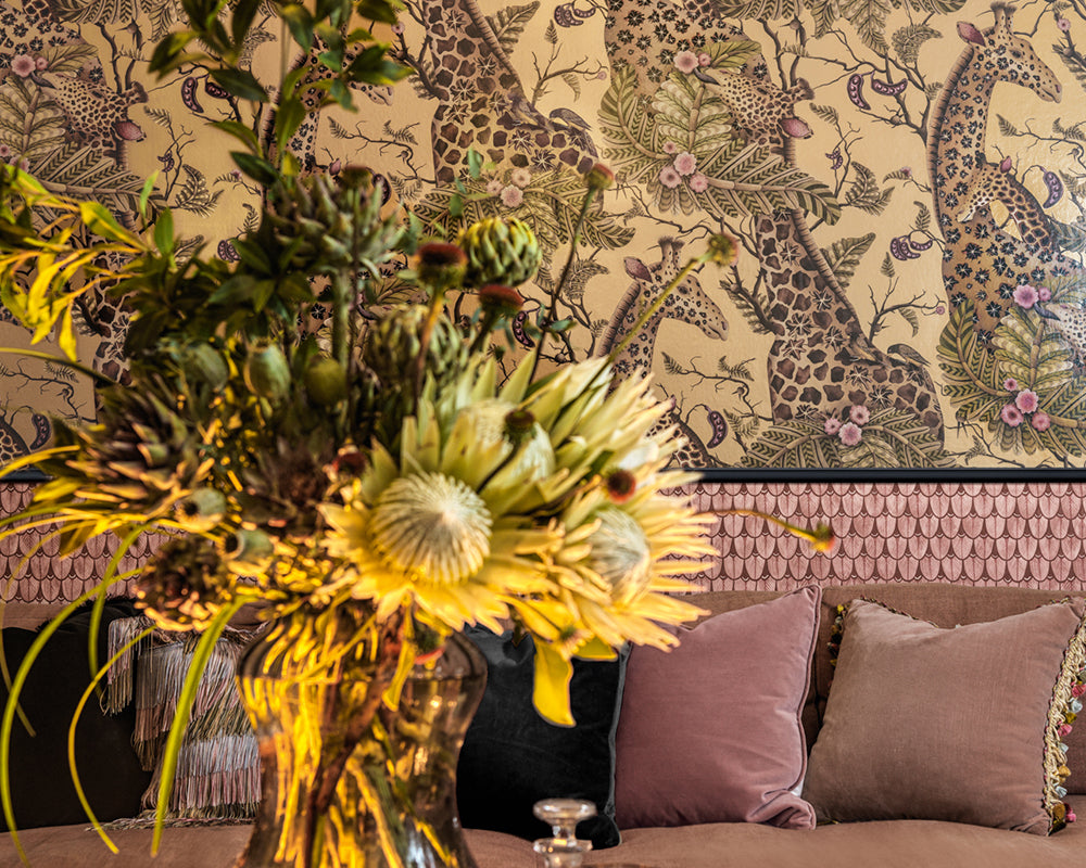 Decorative floral arrangement in a gold vase against the patterned Cole & Son Narina Wallpaper with pink and brown tones.