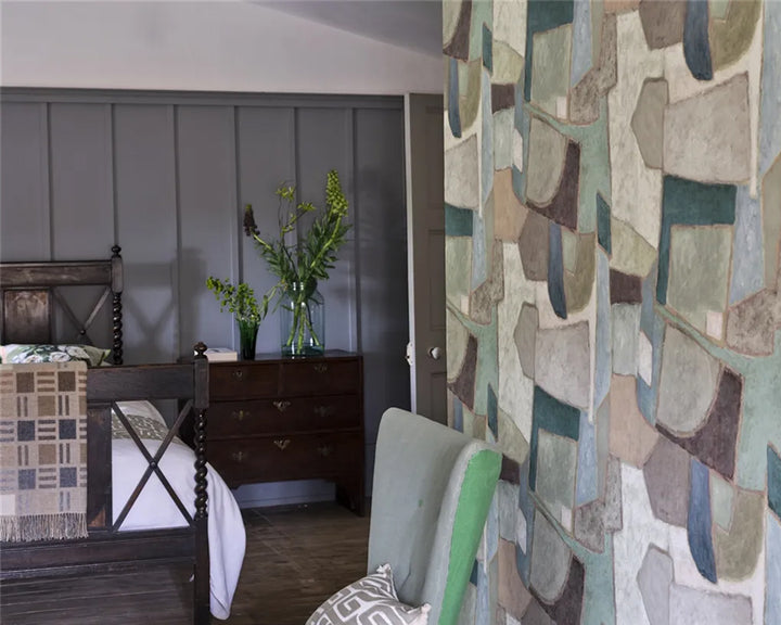 Bedroom with wooden bed, dresser, and patterned wall with Designers Guild Clay Collage Wallpaper