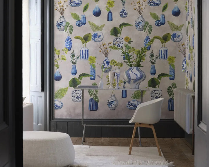 Living room with floral wallpaper, Designers Guild Kawana Wallpaper, featuring blue vases and green leaves.