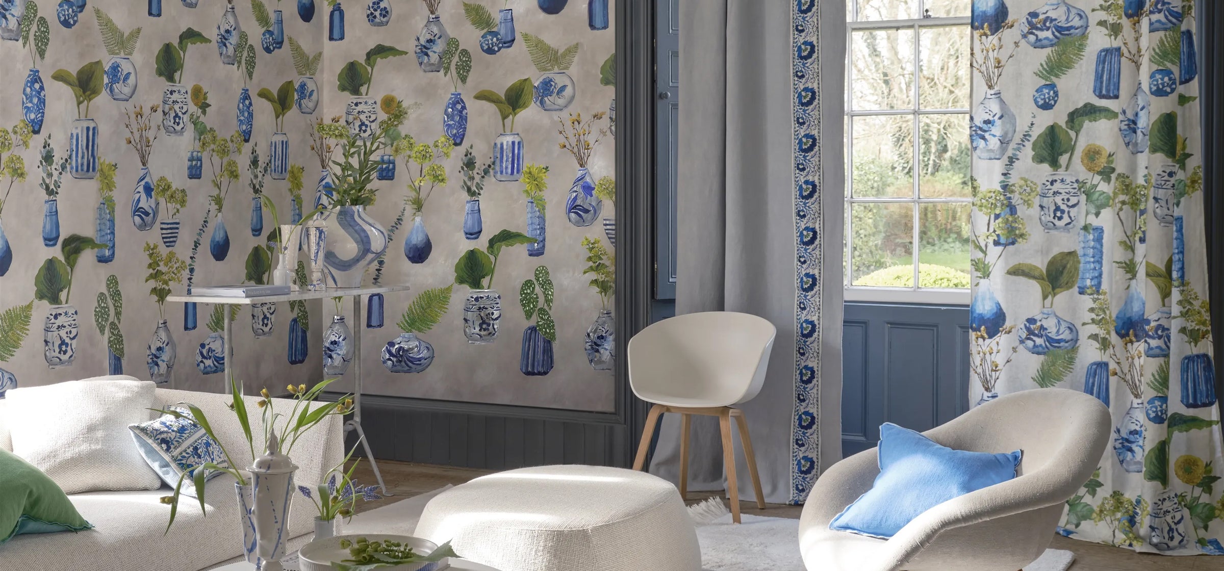 Living room with floral-patterned curtains and Designers Guild Kawana Wallpaper, white furniture, and a plant.