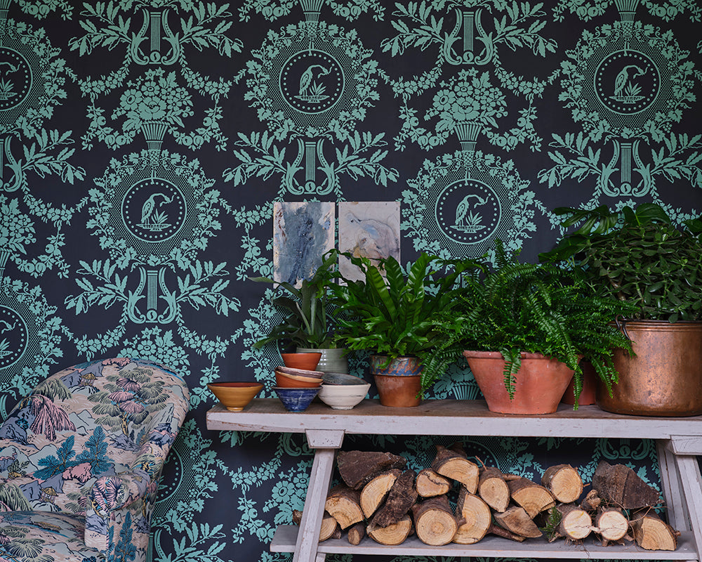 Farrow and Ball Purnon 6205 Wallpaper in a living room setting with logs and plants