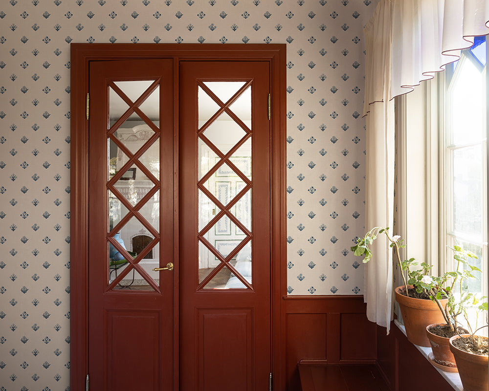 Wooden door with glass panels in a room with patterned Sandberg Amy Wallpaper and plants.