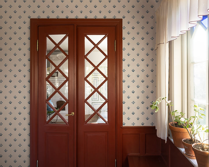 Wooden door with glass panels in a room with patterned Sandberg Amy Wallpaper and plants.
