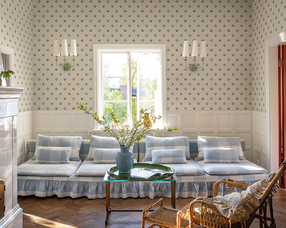 Living room with patterned Sandberg Amy Wallpaper, floral arrangement, and wicker chair.