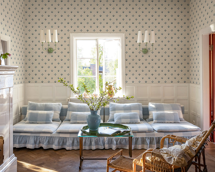 Living room with patterned Sandberg Amy Wallpaper, floral arrangement, and wicker chair.
