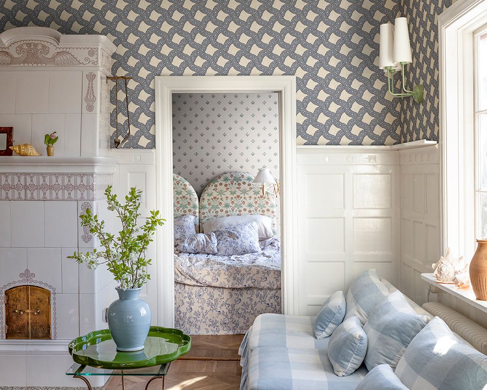 Living room with patterned Sandberg Annie Wallpaper, floral bedspread, and decorative elements.
