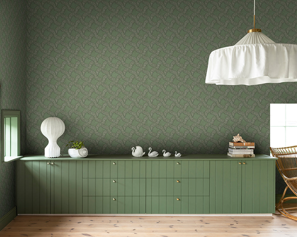 Green cabinet against a patterned Sandberg Annie Wallpaper with decorative items on top