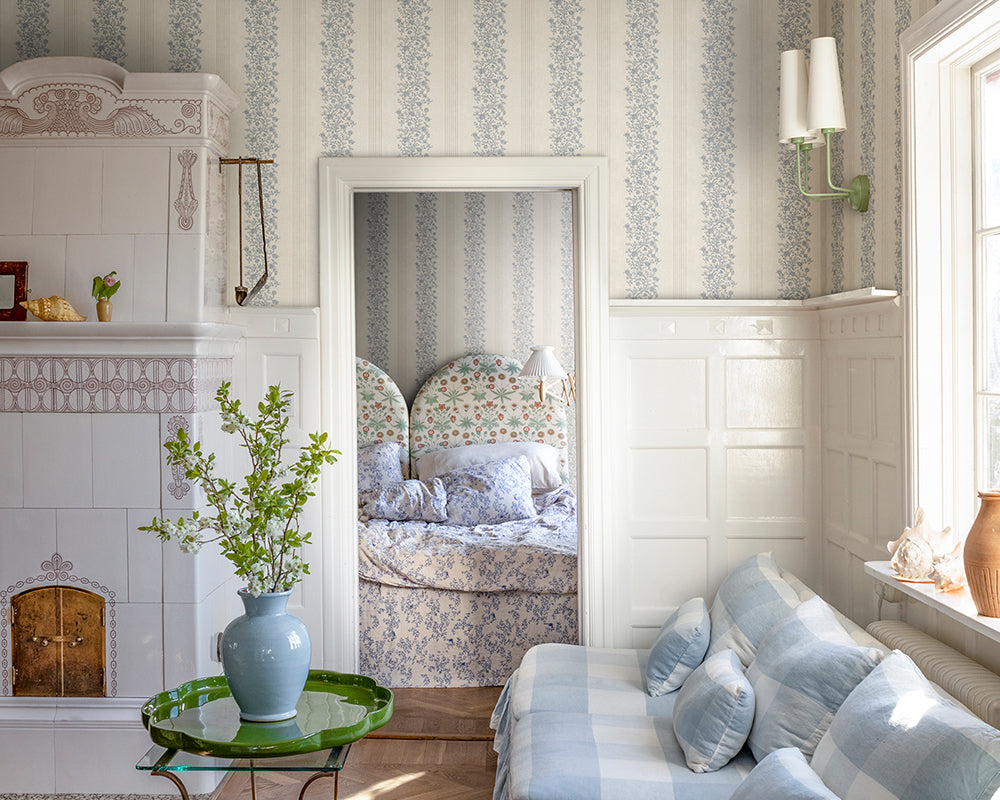 Sandberg Natalie Wallpaper in a living room with a floral bedspread, a white and blue sofa, and decorative elements.