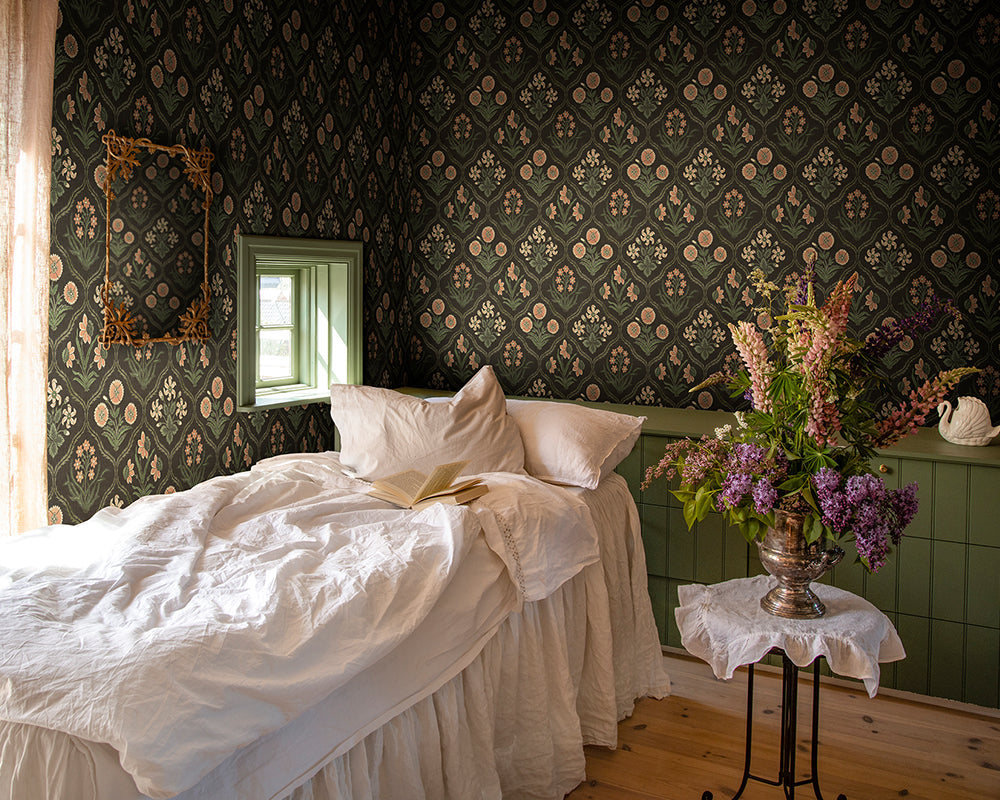 Sandberg Rosa Wallpaper  in a bedroom with  bed with white bedding, and a small table with flowers.