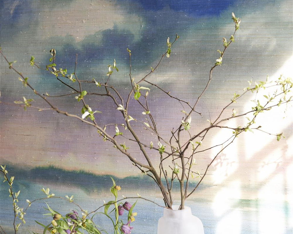 Designers Guild Paysage Marin Grasscloth Wallpaper on a wall behind some foliage