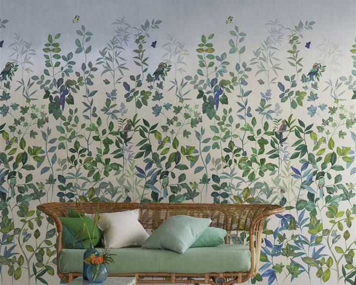 Designers Guild Voliere Wallpaper on a wall behind a wicker sofa