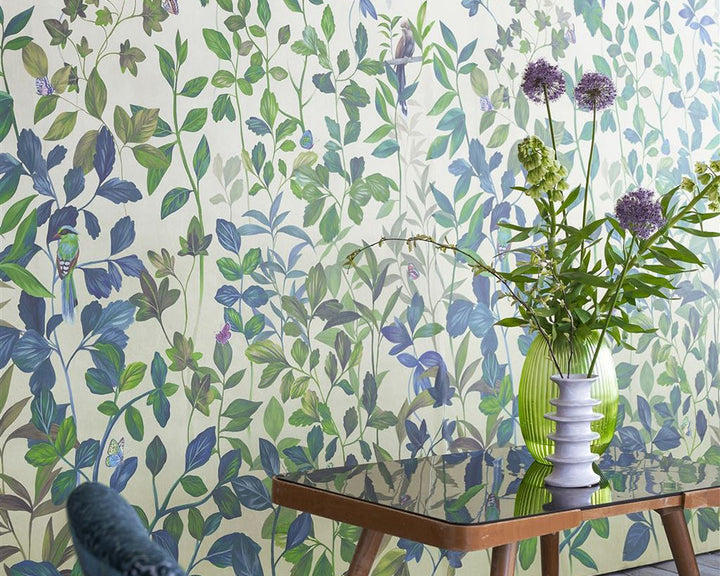 Designers Guild Voliere Wallpaper on a wall behind a chair and table