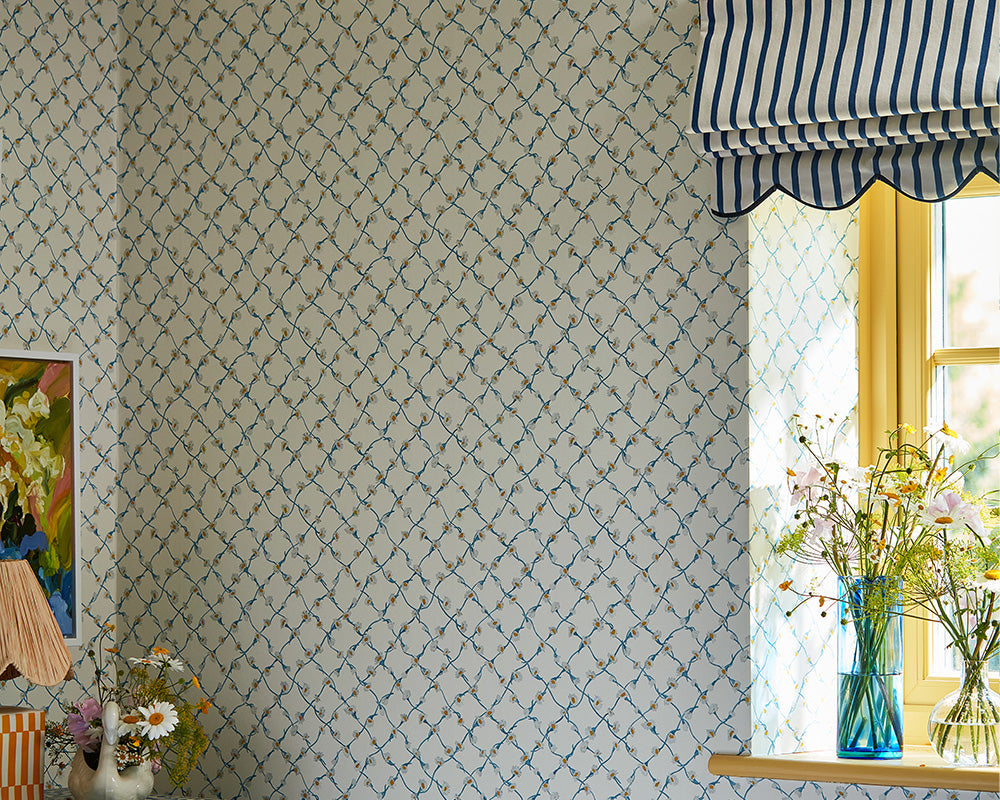 Harlequin Daisy Trellis Wallpaper in a bedroom set up in Lapis/Pearl in background of an armchair by the window