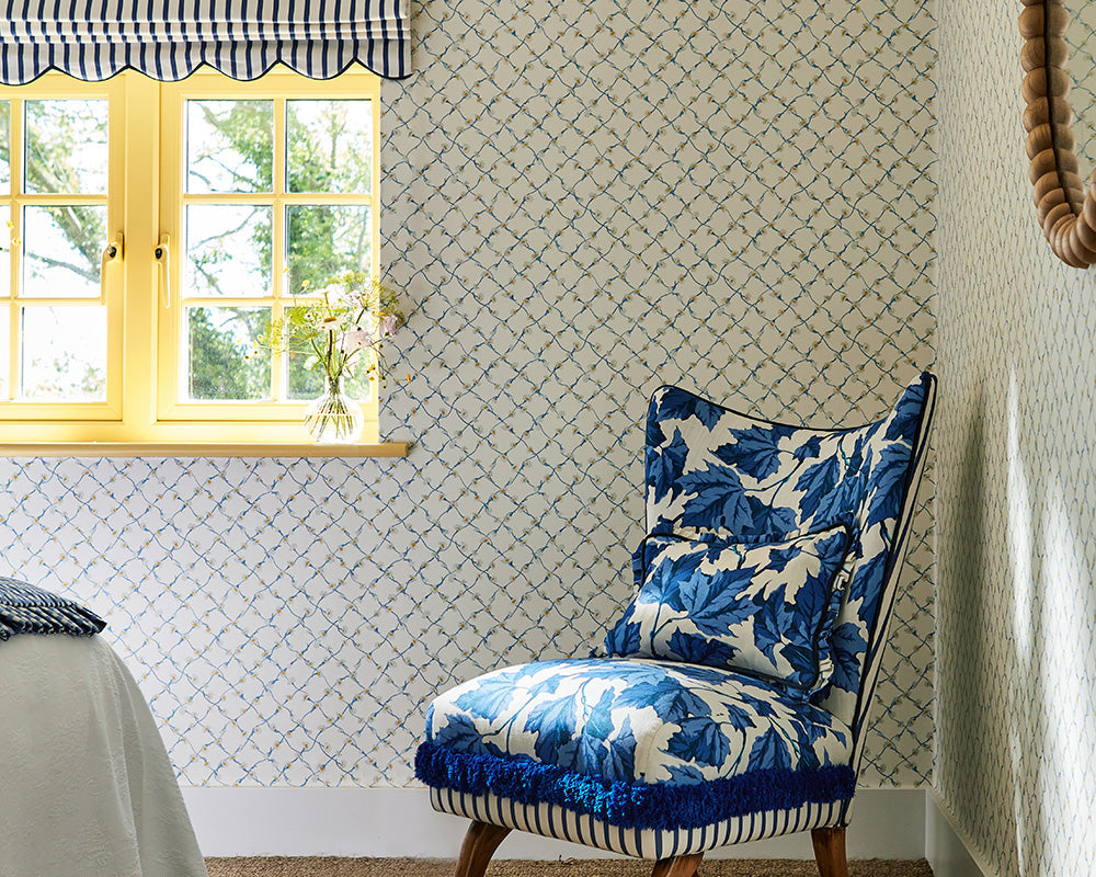Harlequin Daisy Trellis Wallpaper by the window in a bedroom set up in Lapis/Pearl arranged with bouquets of flowers